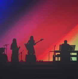 band on stage with rainbow background on screen