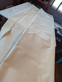 10 oz linen folded and laid on a large artist's table for folding and pinning.,