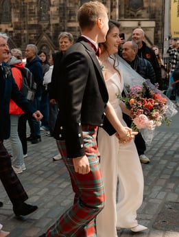 a man and woman in plaidered kilts walking down a street