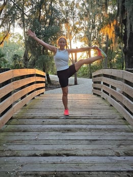 Eva practicing yoga on a wooden bridge at sunset