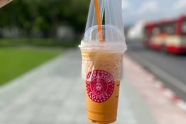 a person holding a cup of coffee in a plastic cup