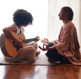 a woman sitting on a mat with a guitar and a guitar