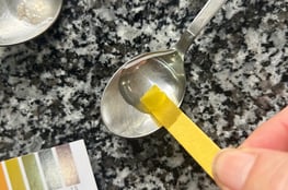 dipping a ph paper strip into brine on a spoon