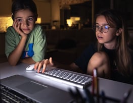 two young girls sitting at a computer desk