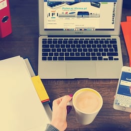 Mãos femininas com café e smartphone em mesa com laptop, Only Goods Pro 2025.