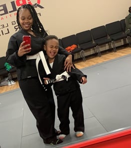 Nurse nova and her super son smiling in the mirror dressed in black karate costumes sharing a warm embrace.