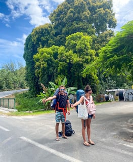 Eva and Laurent hitchhiking on a scenic road in Moorea, French Polynesia.