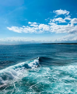 A wave perfectly curling and breaking along the rocky point of Nusa Ceningan.