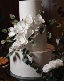 Bolo de casamento elegante com flores brancas e folhagens, ideal para festas e celebrações. Um eleme