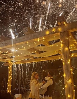 Golden fireworks sparkling behind the wedding cake during the cutting ceremony.