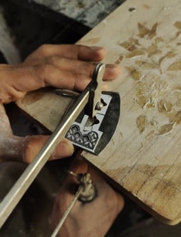 a person is using a pair of scissors to cut a piece of wood