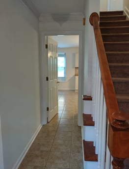 a hallway with a staircase and a tiled floor
