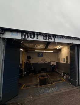 a garage with a garage door open and a sign that says MOT Bay