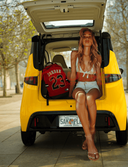 young woman sits in the rear hatch opening of Impulse Electromotive Nano-3 Micro EV car