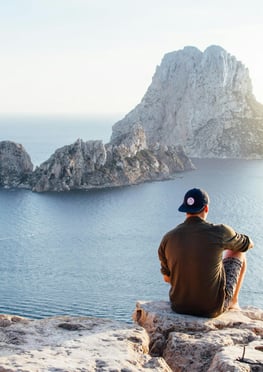 a man sitting on a rock formation in the ocean
