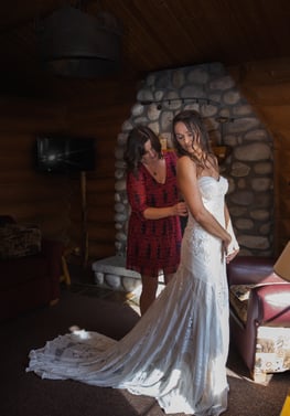 Bride getting wedding dress on in a cabin in jasper