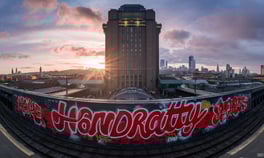a train station with "HANDRATTY" graffiti on the side of the tracks