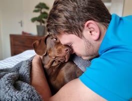 An autistic male adult cuddling a dog