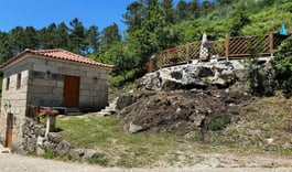 a small stone building with a stone wall and a small stone building