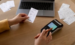 A person using a smartphone to pay bills, with a focus on the bill payment app or website for VA