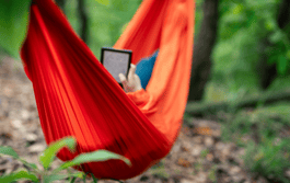 a person reading on an ereader in a hammock