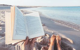 a person reading a book on a beach