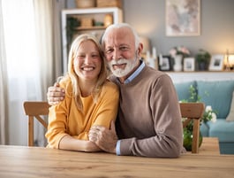 A grandparent sitting at the table hugging his autistic young adult granddaughter