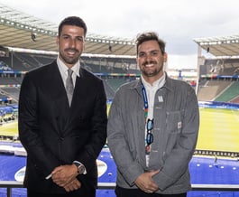 Sami Khedira (ex German footballer) and Tim Dougill posing for a photo in front of Berlin Stadium.