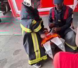 A professional firefighter helps a child from the creative workshop put on a firefighter uniform to 