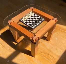 "Handmade hardwood joinery coffee table with curved glass top—modern woodworking by ElkRidge Studio.