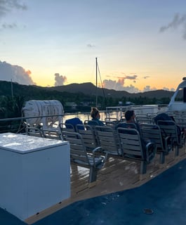 Ferry sailing at sunrise with warm golden light over calm waters in French Polynesia.