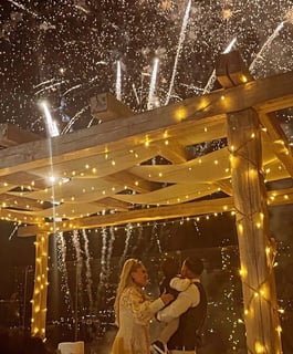 Golden fireworks sparkling behind the wedding cake during the cutting ceremony.