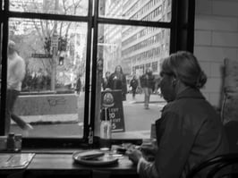A woman looks through a window from a Sydney coffee shop.