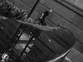 A man walks by a stone wall with reflections