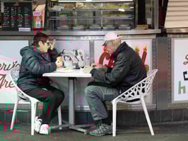 Man and woman sitting at outdoor cafe table.