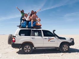 Group of friends sitting on the roof of a 4x4 in the Uyuni Salt Flat.