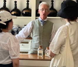 Man in colonial costume serving customers in a shop