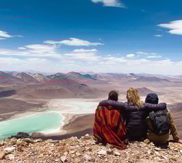 Three friends seen from behind facing Laguna Verde at the summit of Licancabur volcano.