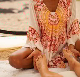a woman sitting on a blanket doing reiki on a patient's feet