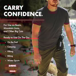 Man hiking in river with bear spray holstered. 