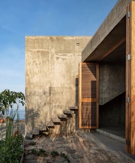 a concrete wall with stairs leading to a concrete house with wood features Rhodes Greece