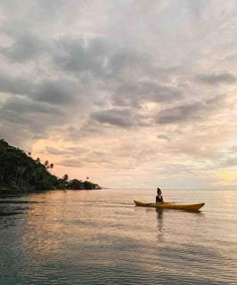 Eva canoeing during a sunset on the lagoon of Taha'a, French Polynesia.