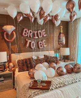 Luxury hotel room decorated with “Bride to Be” banners, balloons, and fresh flowers.