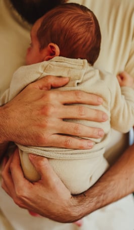 le père qui tient son nouveau né dans les bras