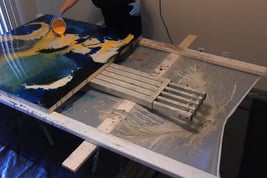 a person is painting a large painting on a table