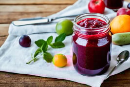 a jar of fruit juice with a spoon and spoon