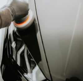 a person polishing a car's hood- buffing a car hood at fix collision center