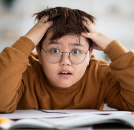 a boy with glasses and a brown sweater