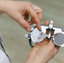 les mains d'un opticien qui règle des verres d'une lunette d'essai pour faire un examen de vue.