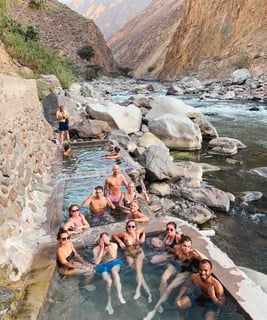 Group of friends swimming in natural pools during the Colca Canyon trek in Peru.